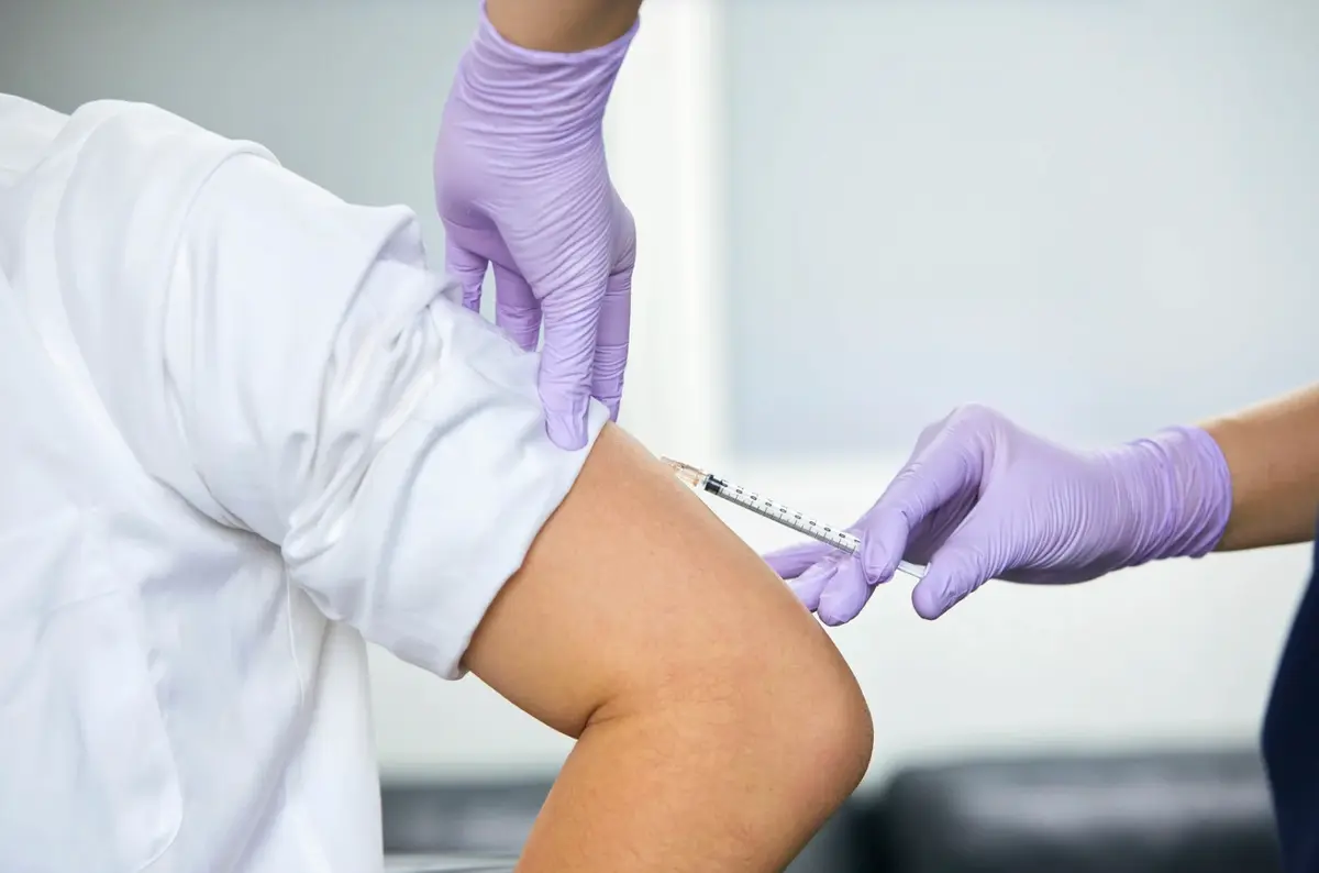 A patient receiving a vaccine from a gloved clinician